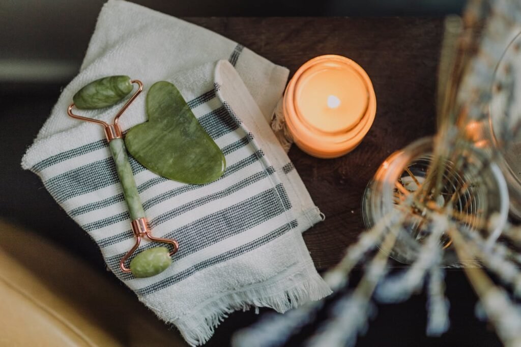 A serene spa setup featuring a jade roller, gua sha, towel, and candle for ultimate relaxation.